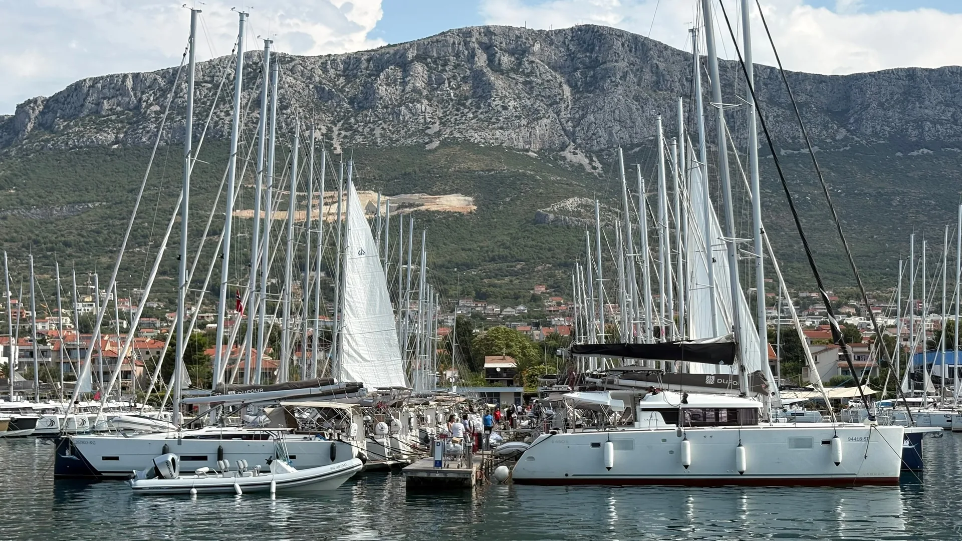 Charter sailing boats and a catamaran on the pontoons at Marina Kaštela, Croatia, with the Kozjak hills behind